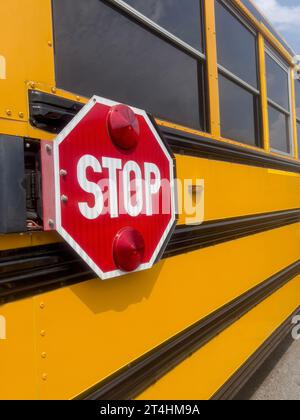 Stop, Nahaufnahme von der Seite Stoppschild auf dem berühmten gelben Retro-Schulbus in den Vereinigten Staaten von Amerika. Hintergrund des Back-to-School-Konzepts mit aktiviertem Kopierraum Stockfoto