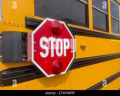 Stop, Nahaufnahme von der Seite Stoppschild auf dem berühmten gelben Retro-Schulbus in den Vereinigten Staaten von Amerika. Hintergrund des Back-to-School-Konzepts mit aktiviertem Kopierraum Stockfoto