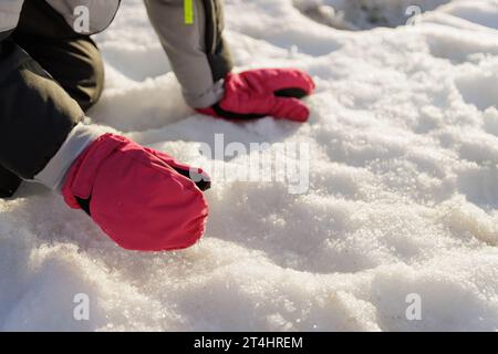 Nahaufnahme von Kinderhänden mit Schneehandschuhen, die Schnee aufsaugen Stockfoto