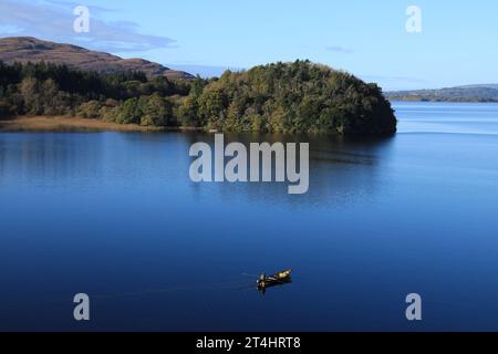 Landschaft in Lough Gill, County Leitrim und County Sligo, Irland, wo man am Herbsttag von einem kleinen Boot aus in noch reflektierenden Gewässern fischen kann Stockfoto