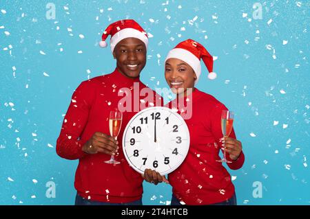 Paare In Santa Hats Mit Champagnergläsern Und Uhr, Studio Stockfoto