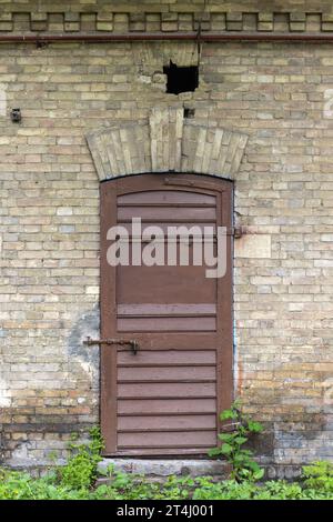 Verschlossene braune Holztür in alten Ziegelwänden, Vorderansicht, Hintergrundfotos Stockfoto