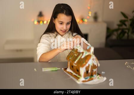 Ein Mädchen spielt mit einem Lebkuchenhaus für traditionelle Weihnachtsdekoration Stockfoto