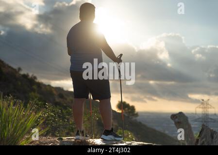 Ein übergewichtiger Mann stoppt sein Training, um die Landschaft am Morgen zu betrachten. Stockfoto