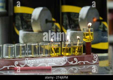 Eine leuchtende Hanukka-Menora, die mit kleinen Ölflaschen beleuchtet wurde, brennt in einem Geschäft in Jerusalem während der Feier des Lichterfestes in Israel. Stockfoto