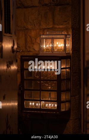 Glühende Hanukkah-Menorahs, beleuchtet mit kleinen Röhrchen mit Ölbrand in einem schützenden Glasgehäuse außerhalb eines Wohngebäudes in Jerusalem während der Feierlichkeiten Stockfoto