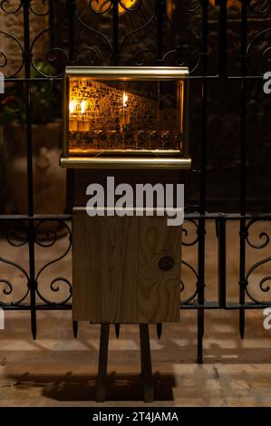 Eine leuchtende Hanukkah-Menora, die mit kleinen Ölröhrchen beleuchtet ist, brennt in einem schützenden Glasgehäuse vor einem Haus in Jerusalem während der Feier der Fes Stockfoto