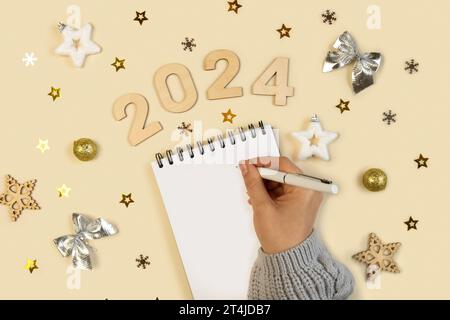 Neujahrsziele 2024. Aufgabenliste. Leeres Notizbuch am Schreibtisch mit Weihnachtsdekoration. Draufsicht. Weibliche Hand Erstellt Plan, Lösung. Neues Leben, Start U Stockfoto