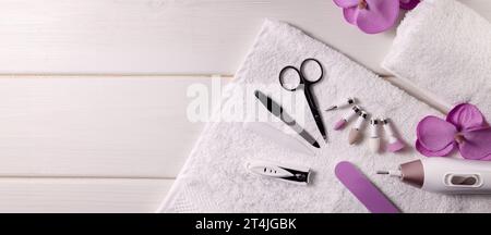 Maniküre-Pediküre-Werkzeugsatz. Nagelbohrmaschine mit Zubehör auf weißem Tisch. Banner mit Kopierbereich. Nagelpflegesalon Stockfoto