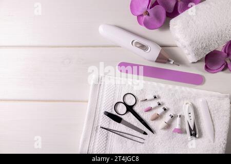 Maniküre-Pediküre-Werkzeugsatz. Akku-Nagelbohrmaschine mit Zubehör auf weißem Tisch mit Kopierraum. Nagelpflege Stockfoto