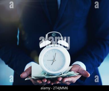 Zeit ist kostbar. Ein nicht erkennbarer Geschäftsmann, der allein im Büro steht und einen Wecker hält. Stockfoto