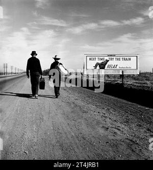 Dorothea Lange: Richtung Los Angeles, Kalifornien. Das Bild zeigt zwei Migranten, die auf einer Feldstraße in der Nähe eines historischen Werbetafens für Southern Pacific Co per Anhalter unterwegs sind Stockfoto