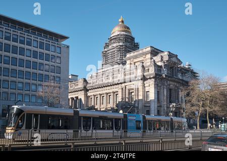 Eine Straßenbahn auf den Gleisen vor dem Justizpalast, einem großen verlassenen Gerichtsgebäude in Brüssel, Belgien. Stockfoto