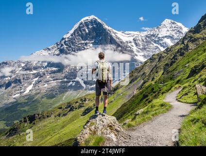Einsamer Wanderer, der die Eiger-Nordwand neben einem Wanderweg über Grindelwald bewundert Stockfoto