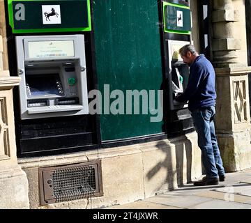 Mann am Geldautomat Lloyds mit 2. Automaten frei, City Street Oxford, UK Stockfoto