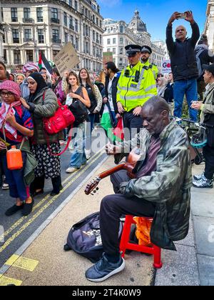 Israel-Gaza-Krieg. Ein Mann spielt Gitarre, während die Demonstranten am 14. Oktober 2023 die Regent Street in London entlang marschieren. Stockfoto