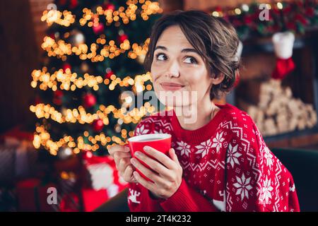 Foto des jungen schönen Mädchens tragen rot hässliche Ornament Pullover trinken Eierlikör Silvester Atmosphäre träumen isoliert drinnen Hintergrund Stockfoto