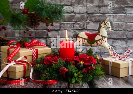 Weihnachtsdekoration mit roter Kerze, Geschenkboxen und Schaukelpferd auf dem alten Holztisch Stockfoto