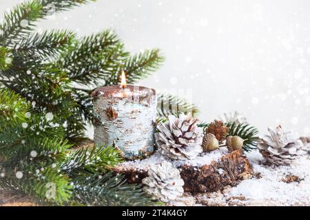 Weihnachtsdekoration mit brennender Kerze, Tannenzweigen und Tannenzapfen Stockfoto