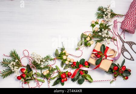 Weihnachtsgeschenke und natürliche Wintergirlanden auf weißem hölzernem Hintergrund Stockfoto