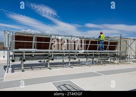 Zwei Bauarbeiter arbeiten an einem adiabatischen Kondensator auf dem Dach eines CO2-Kühllagers (Industriekühlung) Stockfoto