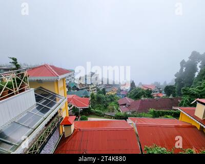 Farbenfrohe Häuser mit Glasoberlichtern, schrägen Dächern für Schnee auf einem Hügel im Himalaya und in Darjeeling, Westen, in die Ferne abgleiten Stockfoto