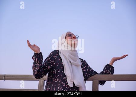 Frauen tragen Hijab und islamische tragen Urlaub im Resort mit einem Lächeln im Gesicht und wunderschönen, verschwommenen Lichtern im Hintergrund Stockfoto