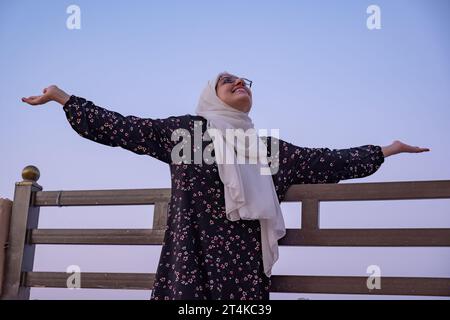 Frauen tragen Hijab und islamische tragen Urlaub im Resort mit einem Lächeln im Gesicht und wunderschönen, verschwommenen Lichtern im Hintergrund Stockfoto