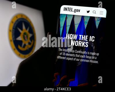 Person, die ein Mobiltelefon mit Webseite der Agenturgruppe United States Intelligence Community (IC) mit Siegel hält. Konzentrieren Sie sich auf die Mitte des Telefondisplays. Stockfoto