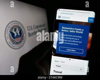 Person, die ein Mobiltelefon mit Webseite der Behörde United States Customs and Border Protection (CBP) mit Siegel hält. Konzentrieren Sie sich auf die Mitte des Telefondisplays. Stockfoto