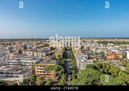 Luftaufnahme von Brindisi, Italien, mit Wohngebäuden, von Bäumen gesäumten Straßen und der Adriaküste unter einem klaren blauen Sommerhimmel. Stockfoto