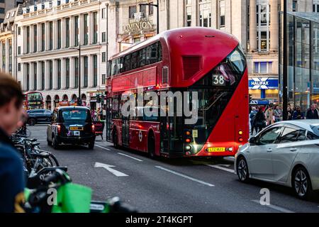 London, England, 5. Oktober 2023: Ein moderner elektrischer Doppeldeckerbus und ein altes Taxi fahren an der Charing Cross Road in der New Oxford Street vorbei. Stockfoto