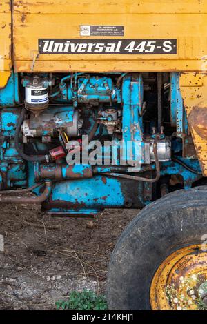 Nahaufnahme des Traktormotors Universal 445s. Oldtimer-Traktor in Gelb und Blau mit Komponenten des Dieselmotors. Stockfoto