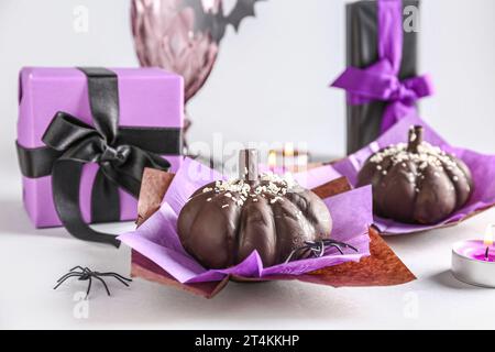 Köstliche Schokoladenkuchen, Geschenkboxen und Spinnen für Halloween-Feier auf weißem Hintergrund, Nahaufnahme Stockfoto