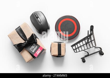 Komposition mit Geschenkboxen, Gadgets und kleinem Einkaufswagen auf hellem Hintergrund. Cyber Monday-Angebot Stockfoto