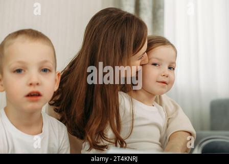 Liebevolle Frau, die zu Hause Tochter küsst Stockfoto