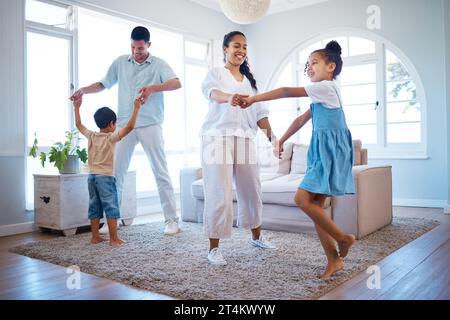 Energiegeladene junge Eltern tanzen mit ihren beiden Kindern zu Hause. Glückliche hispanic-Familie, die Spaß hat und Zeit zusammen in ihrem Wohnzimmer verbringt Stockfoto