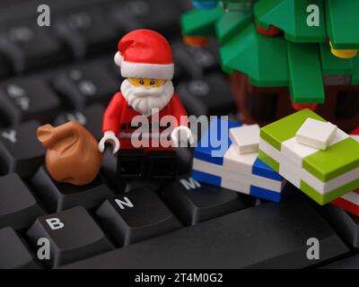 Tambow, Russische Föderation – 31. Oktober 2023 Eine Minifigur aus Lego Santa Claus, die auf einer Computertastatur neben dem Weihnachtsbaum sitzt und einige Geschenke enthält. C Stockfoto