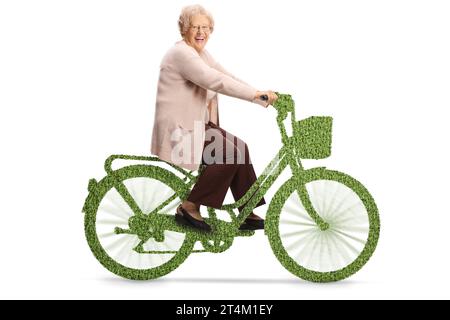 Ältere Dame, die auf einem grünen Fahrrad fährt und in die Kamera lächelt, isoliert auf weißem Hintergrund Stockfoto