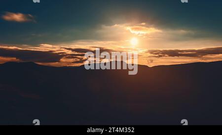 Sonnenaufgang Wolkenlandschaft Himmel über Bergkette Silhouette. Dramatische Wolken fließen in den dunklen Himmel, Sonnenschein geht über den Berggipfel mit goldenen Lichtstrahlen. Wunderschöne Natur am Morgen. Stockfoto