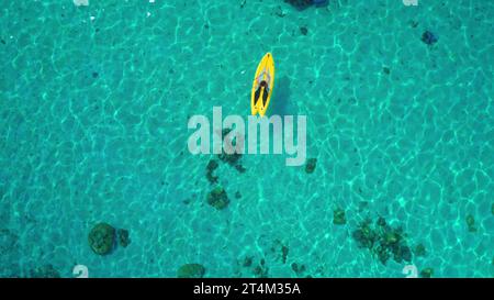 Luftaufnahme von oben nach unten, Person, Paddel gelb sup. Kristallblaues Meerwasser-Korallenriff. Outdoor-Aktivsport Lifestyle Reisen im Sommerurlaub. Natürlicher Hintergrund. Stockfoto