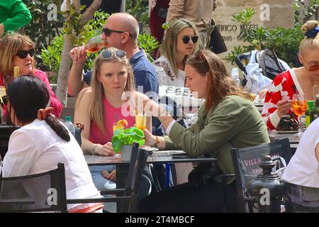 Gruppen von Einzelpersonen, Freunden, Paaren und Touristen aus mehreren Generationen genießen ihre Freizeit in einem Bar Restaurant im Freien in Valletta, Malta. Stockfoto