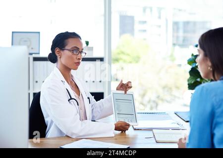 Einbeziehung intelligenter Technologien in ihre Konsultationen. Eine junge Ärztin mit einem digitalen Tablet während einer Konsultation mit ihrem Patienten. Stockfoto