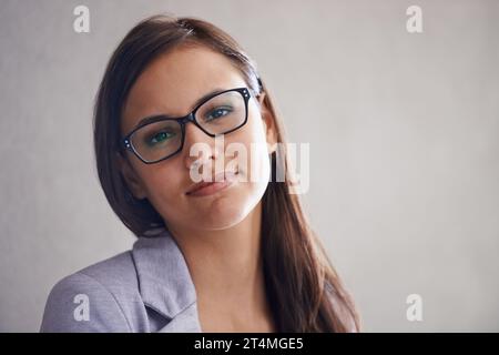 Zufrieden mit ihren Karriereentscheidungen. Porträt einer erfolgreichen jungen Geschäftsfrau, die vor einer grauen Wand steht. Stockfoto