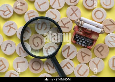 Konzept des englischlernens, der Suche nach Wörtern und Informationen. Englischer Buchstabe und Lupe auf gelbem Hintergrund. Stockfoto