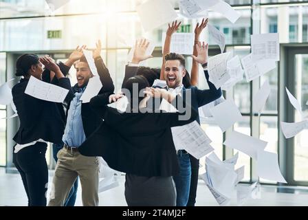 Sie können lustig und albern sein. Eine Gruppe fröhlicher Geschäftsleute, die ihre Hände vor Freude heben, während sie im Büro bei der Arbeit lustig sind. Stockfoto