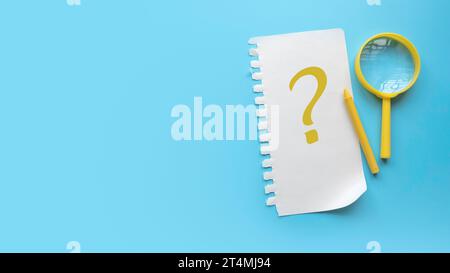 Fragen und Antworten Konzept. QnA und faq. Fragesymbol auf Papier geschrieben. Blauer Hintergrund mit Kopierraum. Stockfoto