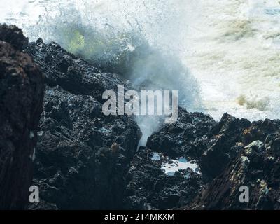 Das Wasser, das durch ein kleines Flöckchen schwingt, wenn die Wellen in Bonville Headland Sawtell NSW Australien einbrechen Stockfoto