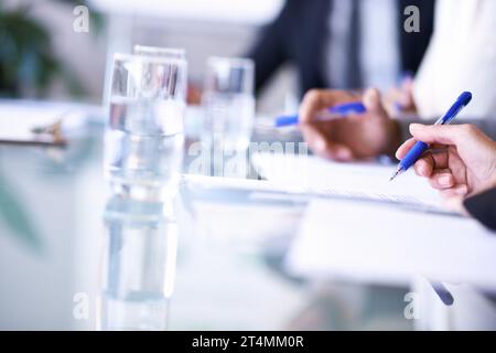 Vertrag unterzeichnen. Zugeschnittene Ansicht einer Gruppe von Geschäftsleuten, die an einem Tisch an einigen Dokumenten arbeiten. Stockfoto