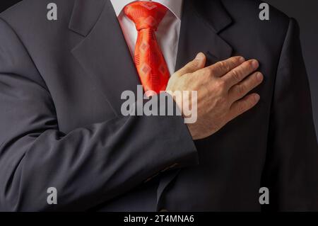 Mann, der formelle Business-Anzug trägt, der mit Hand über Herz schwört Stockfoto